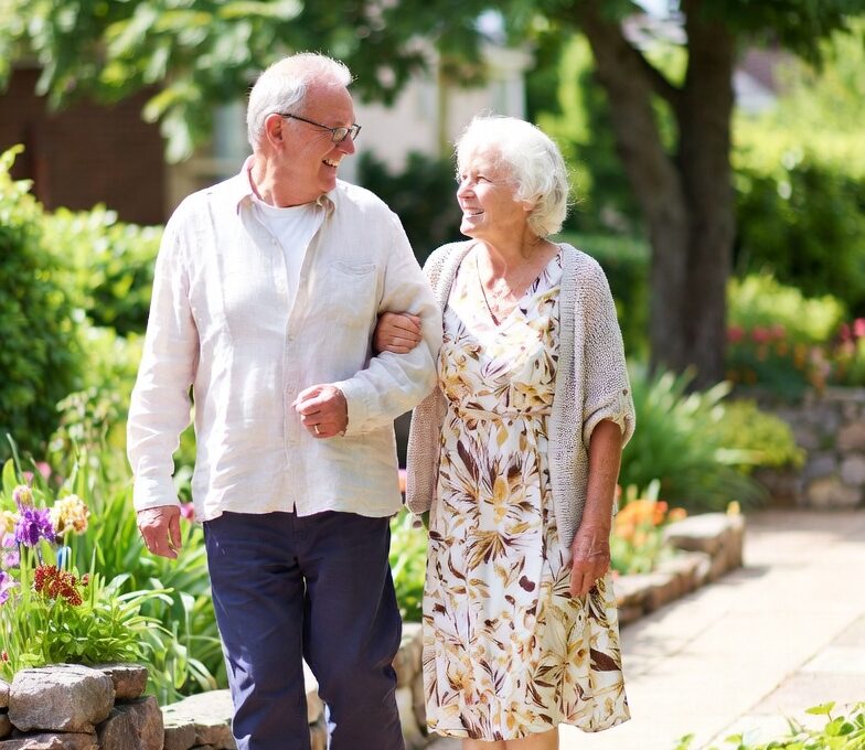 Elderly couple enjoying a leisurely walk in the garden of an independent living community.