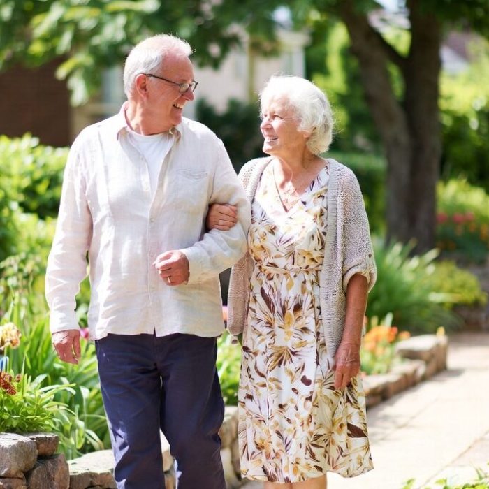 Elderly couple enjoying a leisurely walk in the garden of an independent living community.